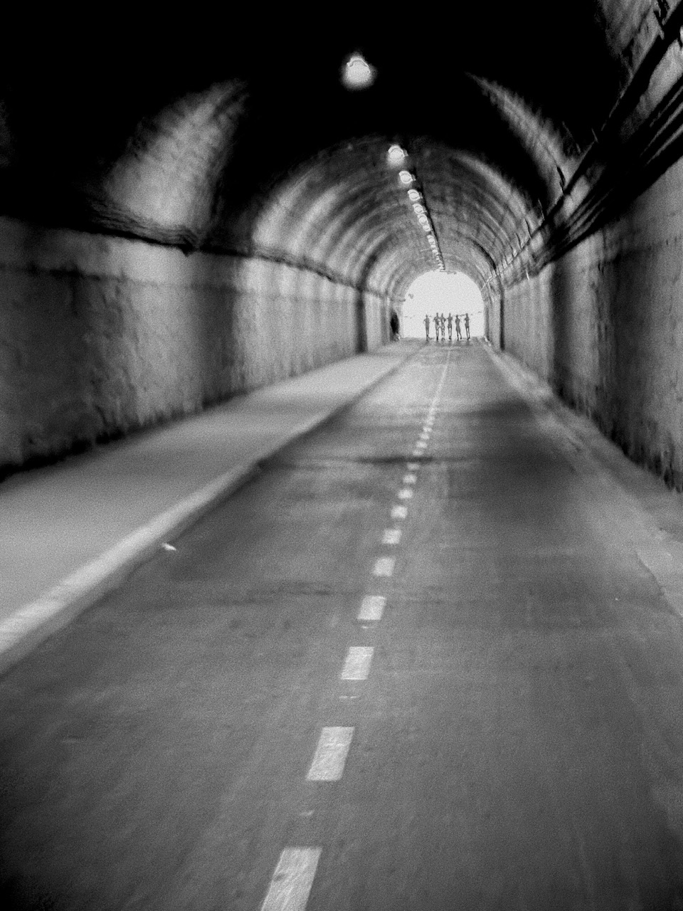 A few human figures at the end of a tunnel.