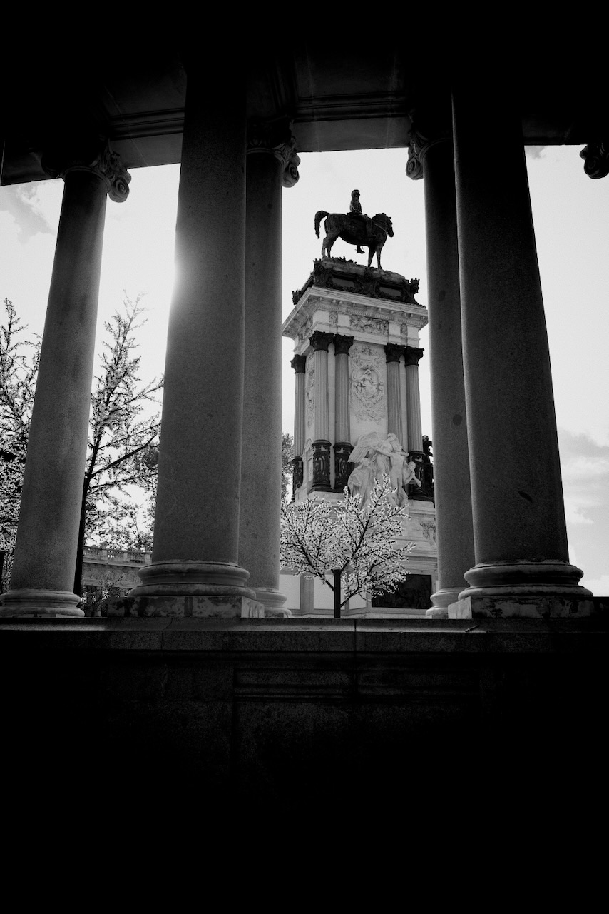 Equestrian statue framed by columns, with trees and sky in the background..