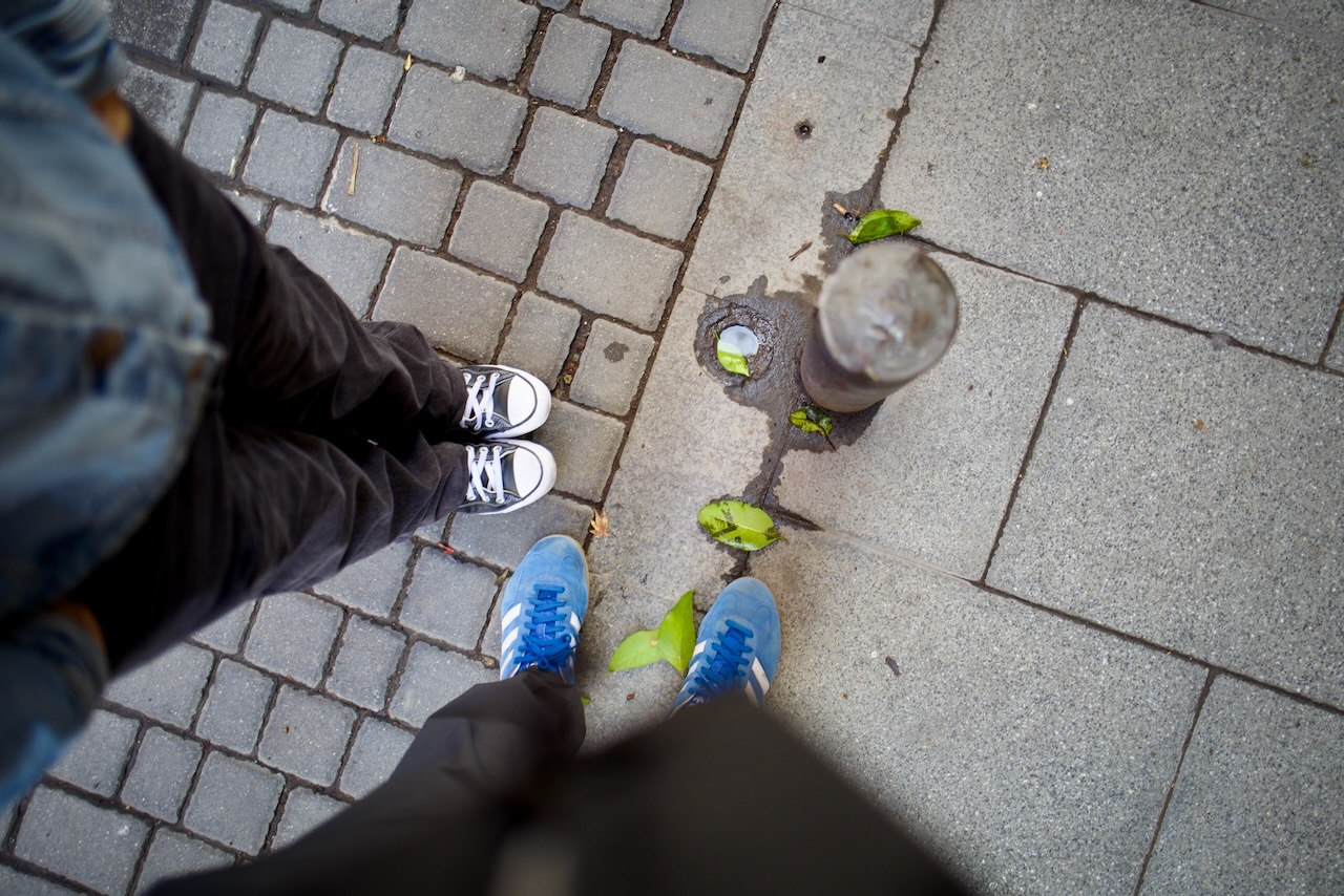 Two people standing near a glass on a paved surface with leaves.